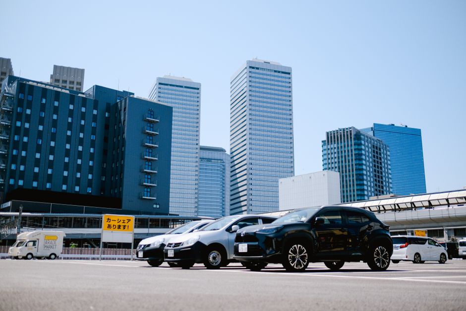晴れた空の下、近代的な建物と駐車された車のある都市の駐車場。
