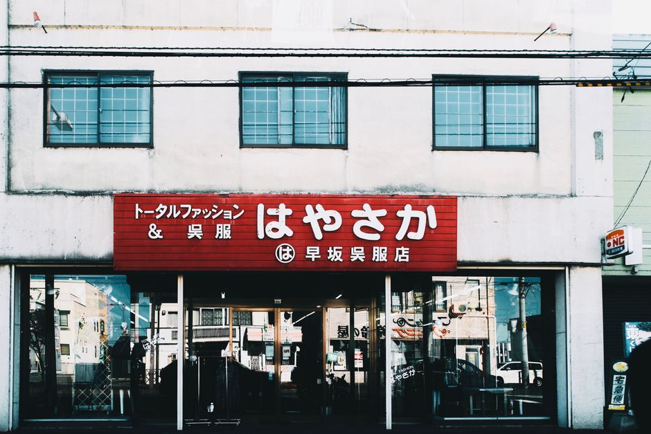 目立つ赤い看板とガラス窓のある日本の衣料品店の街の眺め。