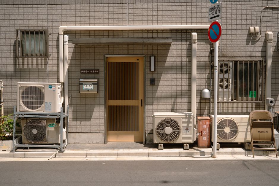 日本の東京にある、エアコンと駐車禁止の標識が特徴的な、ミニマルな外観の建物。