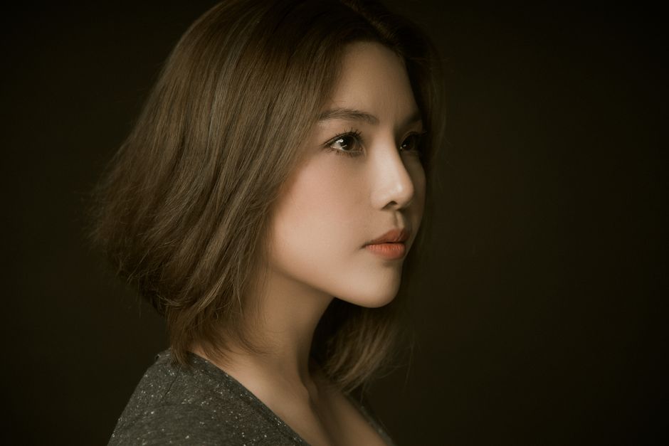 スタジオ設定の暗い背景でポーズをとるエレガントな女性の横顔。