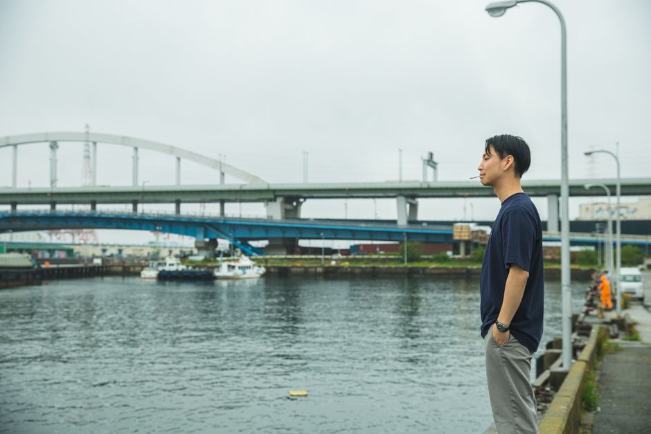 都市大阪にある川のそばで考え込んでいるアジア人男性の側面プロフィール。