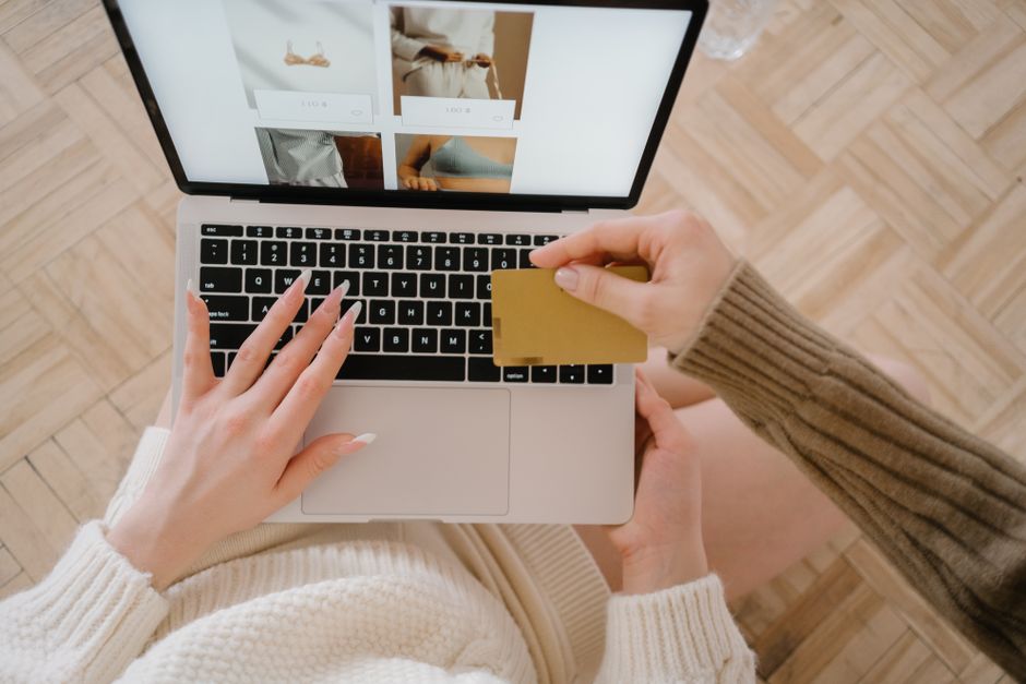 ノートパソコンとクレジットカードを使ってオンラインショッピングをする人、eコマースの便利さを強調しています。
