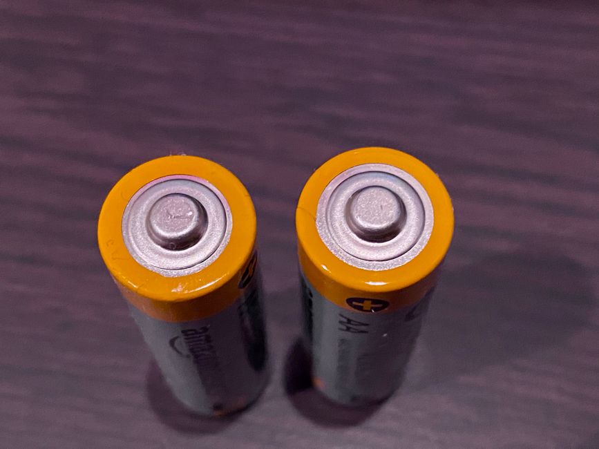 暗い表面に黄色いトップのAA電池2本の上からのビュー。