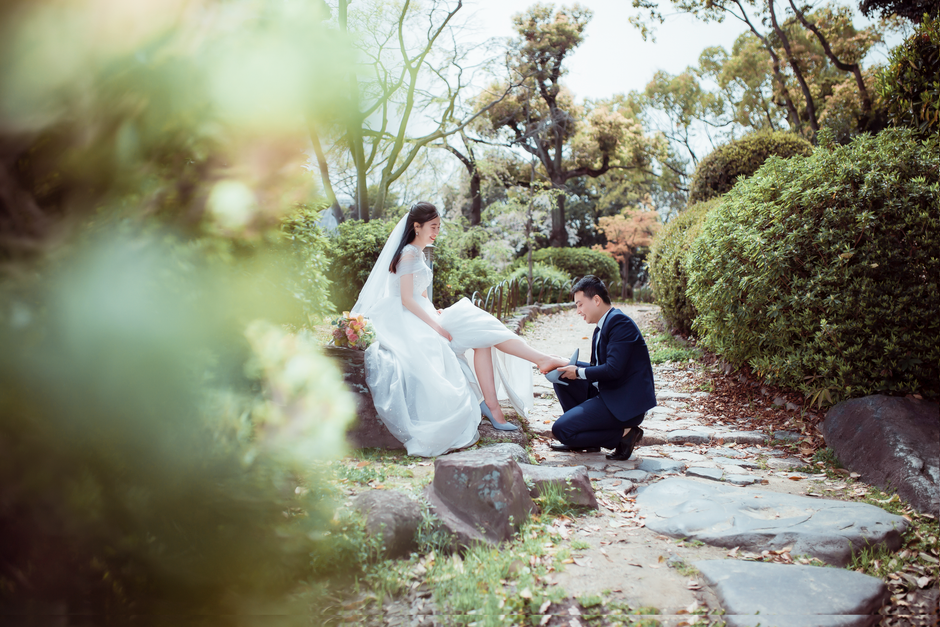 新郎新婦が緑豊かなエリアに囲まれた石の道で優しい瞬間を共有しています。