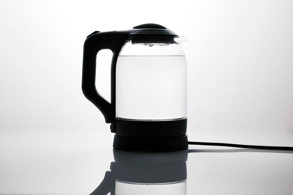 スリムなガラス製電気ケトルに水が入っており、光沢のある表面に反射している。モダンなキッチンに最適。