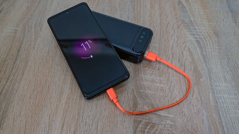 木製テーブルの上でモバイルバッテリーから充電中のスマートフォン