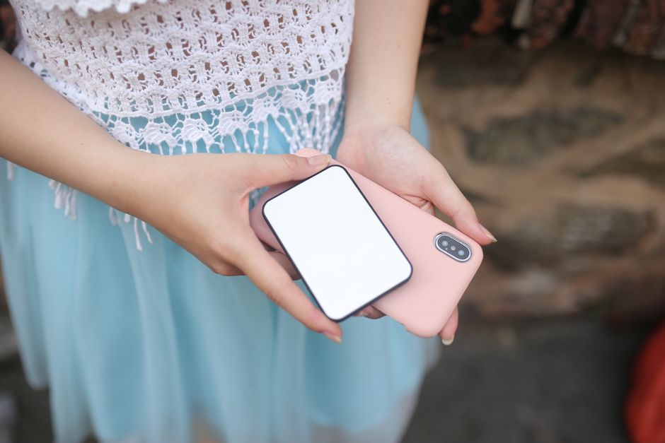 スマートフォンと小型モバイルバッテリーを手に持つ女性