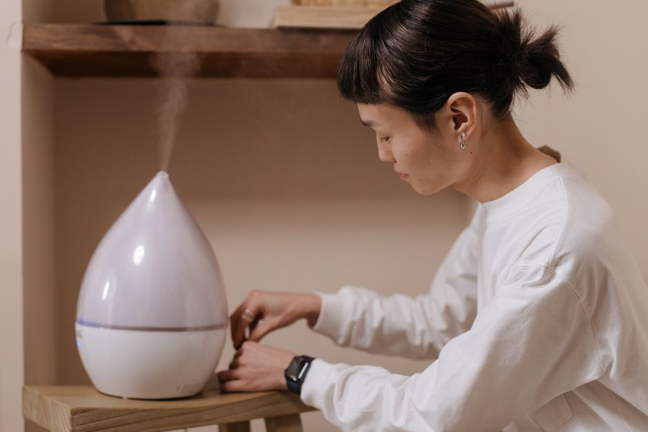 女性が室内で加湿器を調整して、リラックスと空気の質を促進しています。