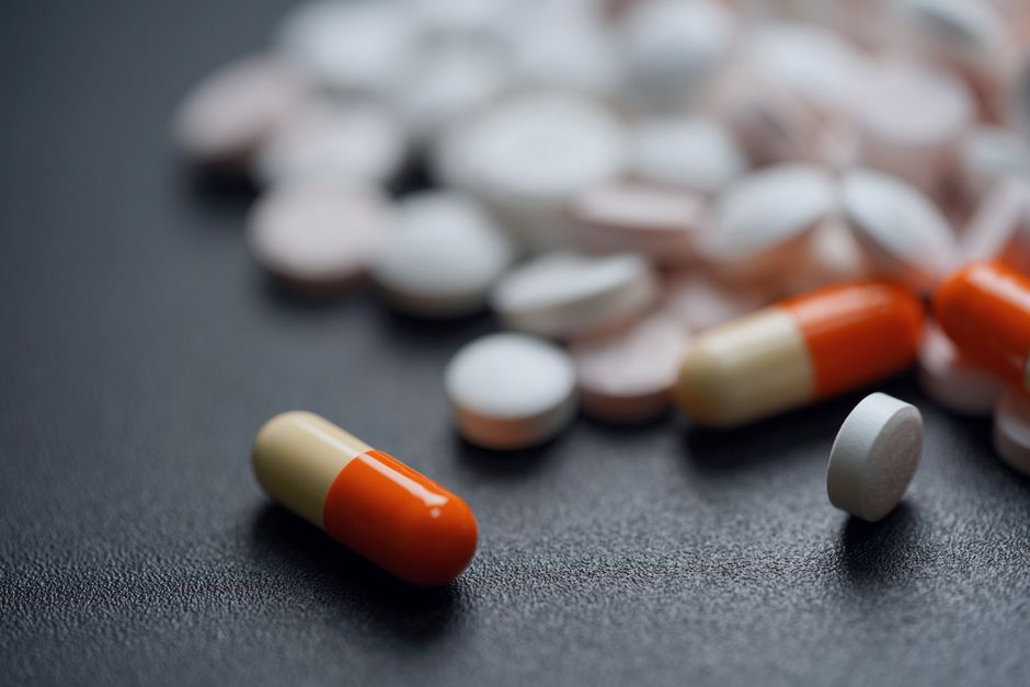 暗い背景にあるさまざまな錠剤とカプセル、薬の多様性を強調しています。